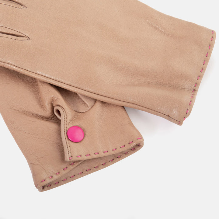 Close-up of a tan leather glove with pink contrast stitching and a bright pink snap button, shown on a clean white background.