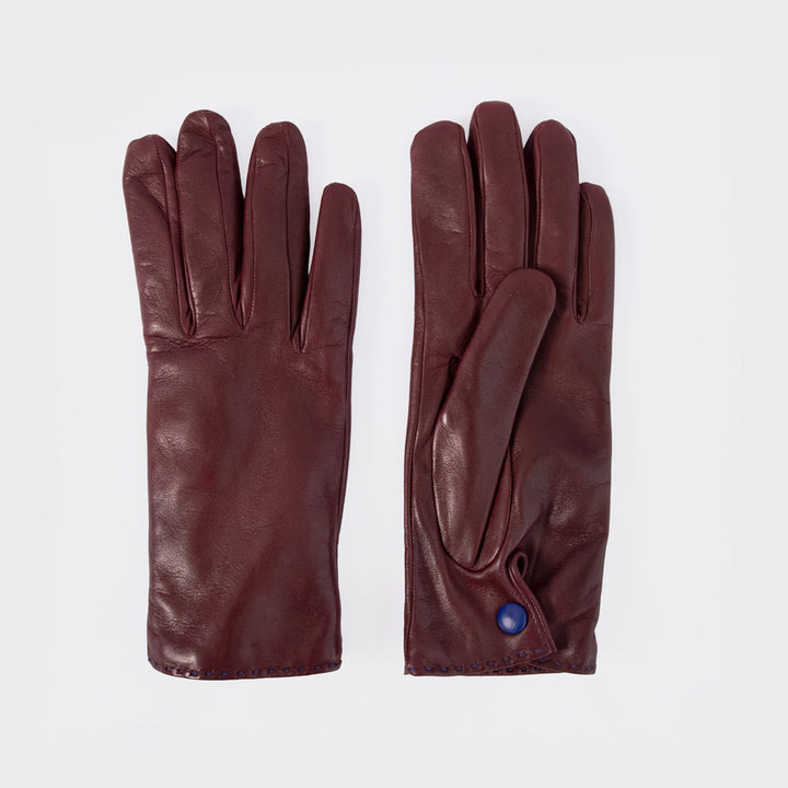 A pair of dark burgundy leather gloves laid flat on a light gray background, showing both the back of one glove and the front of the other with a small blue button detail.