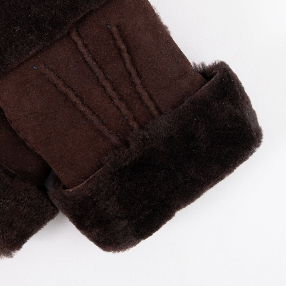 Close-up detail of a dark brown shearling wrist warmer with plush dark brown wool trim, displayed on a clean white background.