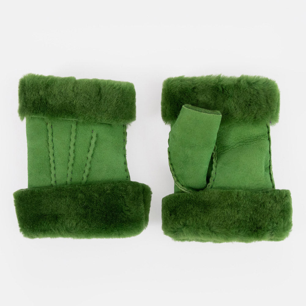 a pair of women's green shearling wrist warmers with suede outer and fluffy wool cuff on a light grey background