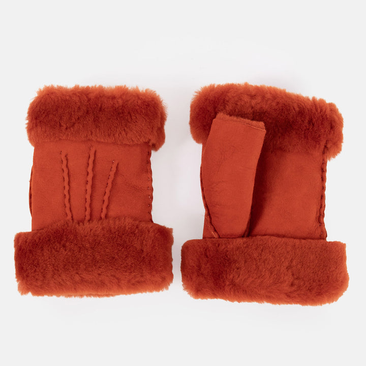 A pair of rust-orange shearling-lined wrist warmers shown flat against a clean white background.