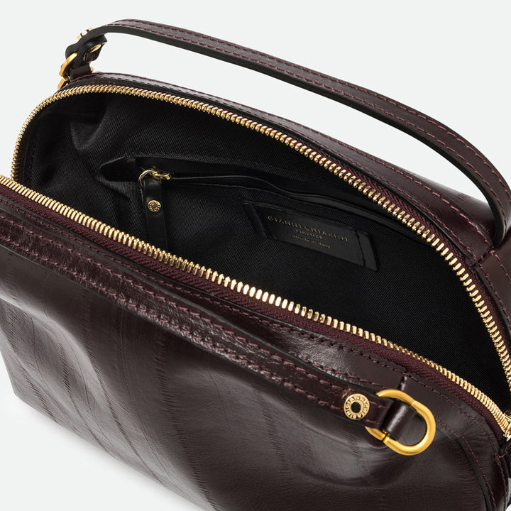 Inside a dark burgundy leather bag showing a black lining, zip pocket and gold zip