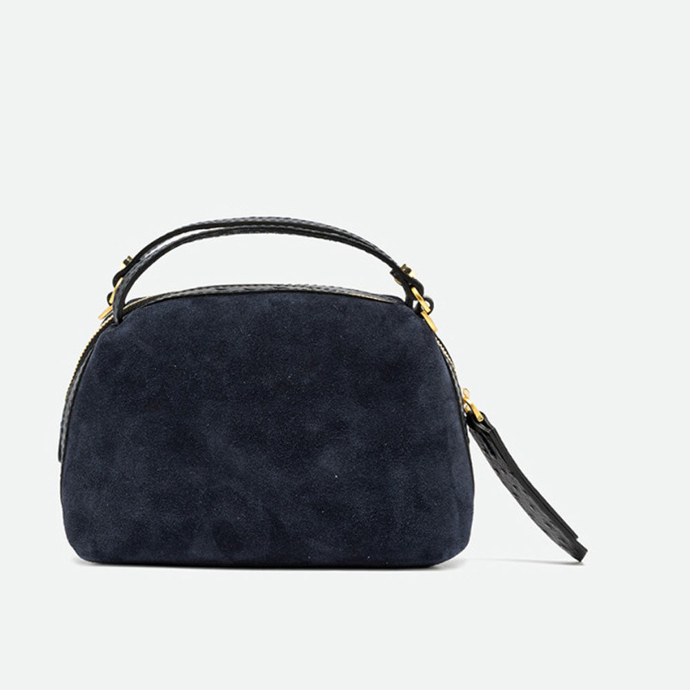 Front of a small navy suede handbag with a rounded shape and black leather handles