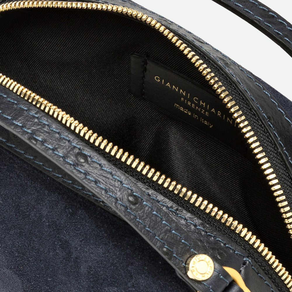 Inside a navy suede bag showing a black lining, gold zip and branded label
