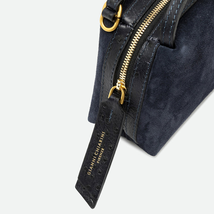 Close-up of a gold zip and black leather pull tag on a navy suede bag