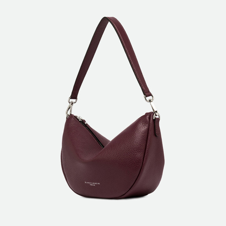 Side view of a burgundy leather half moon shoulder bag