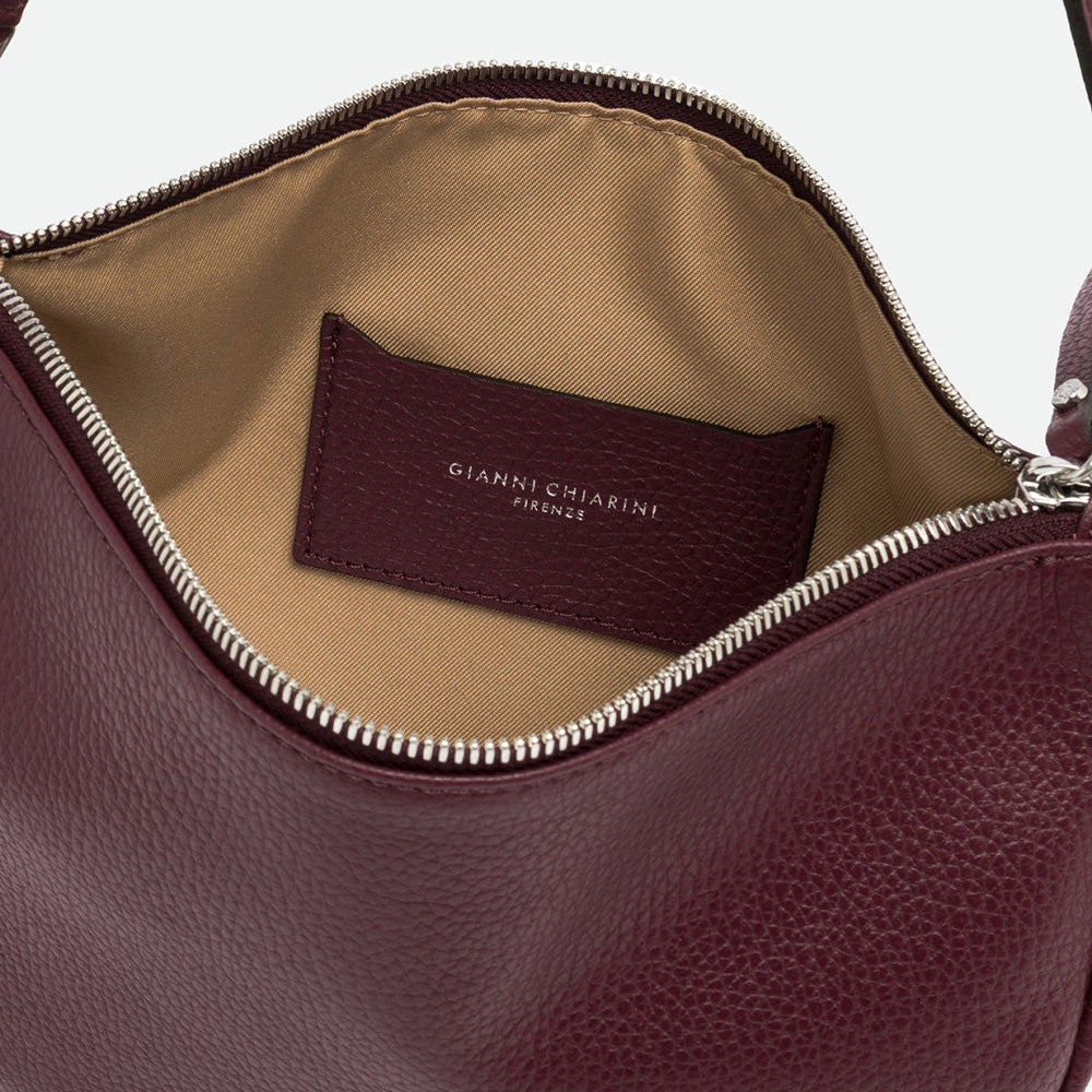 Inside a burgundy leather bag showing a beige lining, burgundy label and silver zip