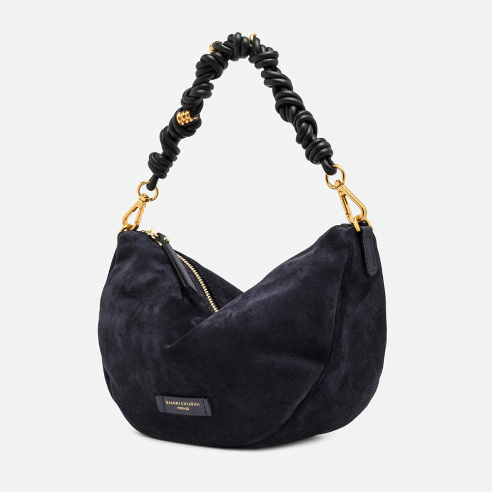 Side view of a navy suede half moon bag with gold clasps