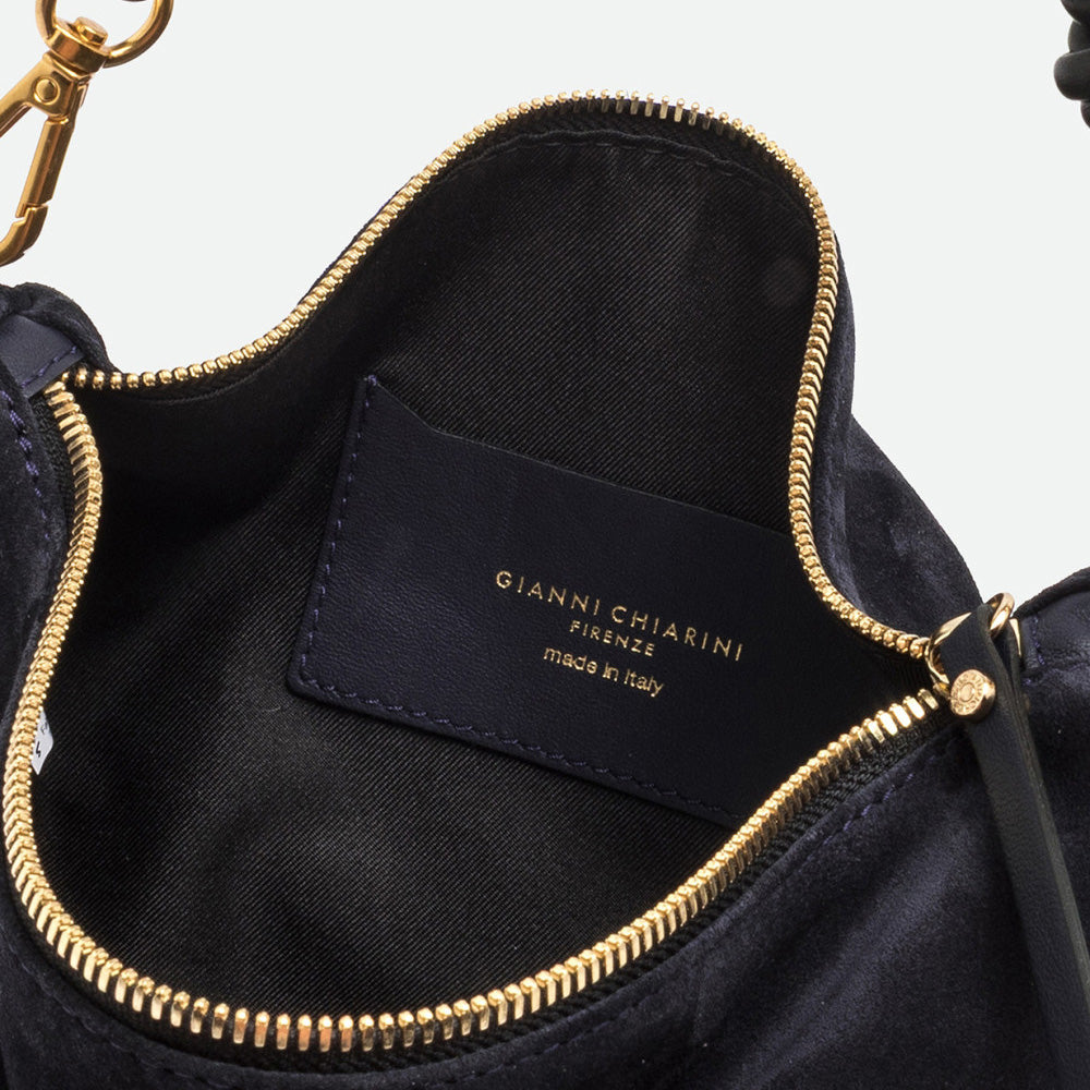 Inside a navy suede bag showing a black lining, gold zip and navy branded label