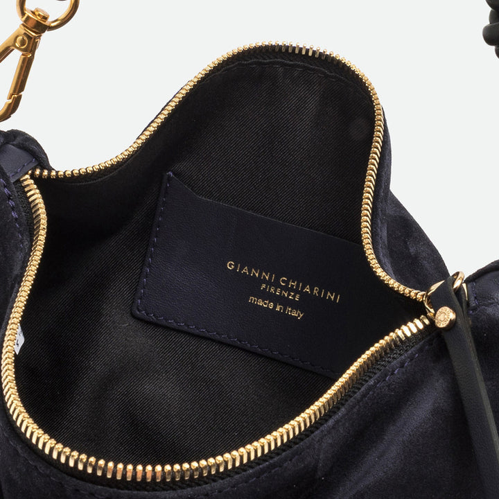 Inside a navy suede bag showing a black lining, gold zip and navy branded label