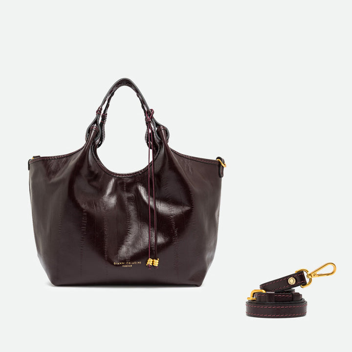 Dark burgundy leather tote with its sides opened out, beside a separate shoulder strap
