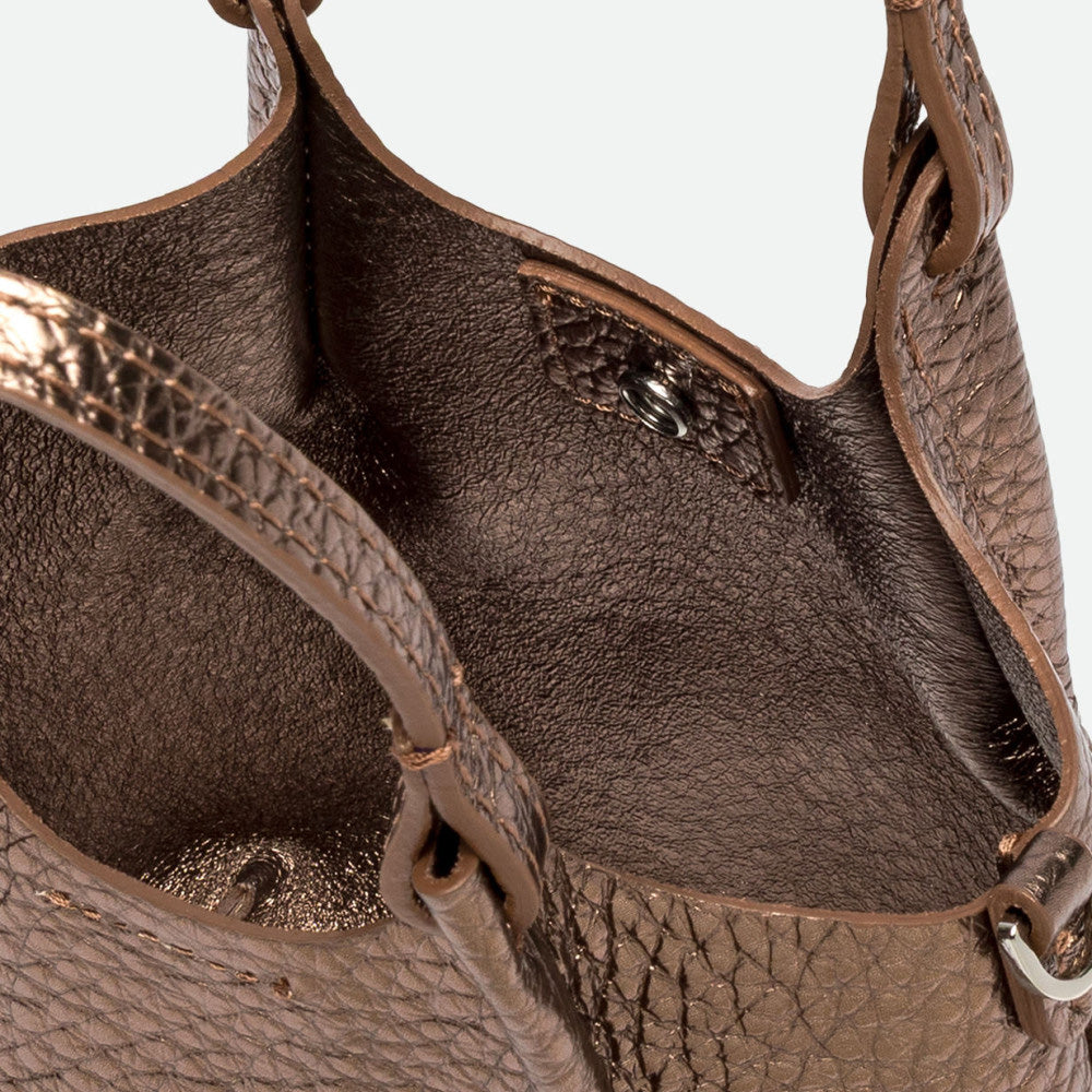 Inside a bronze metallic leather bag showing the unlined interior and magnetic clasp