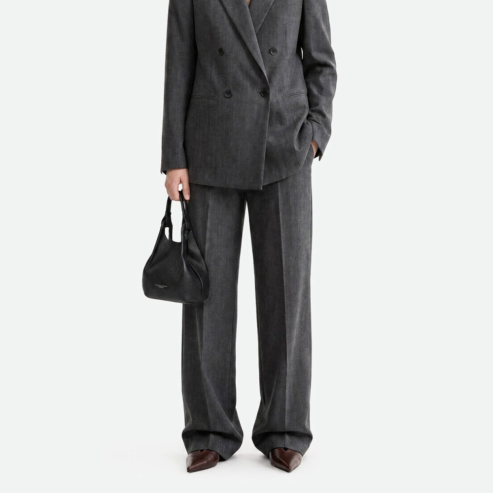 Woman in a grey suit carrying a small black leather bag at her side