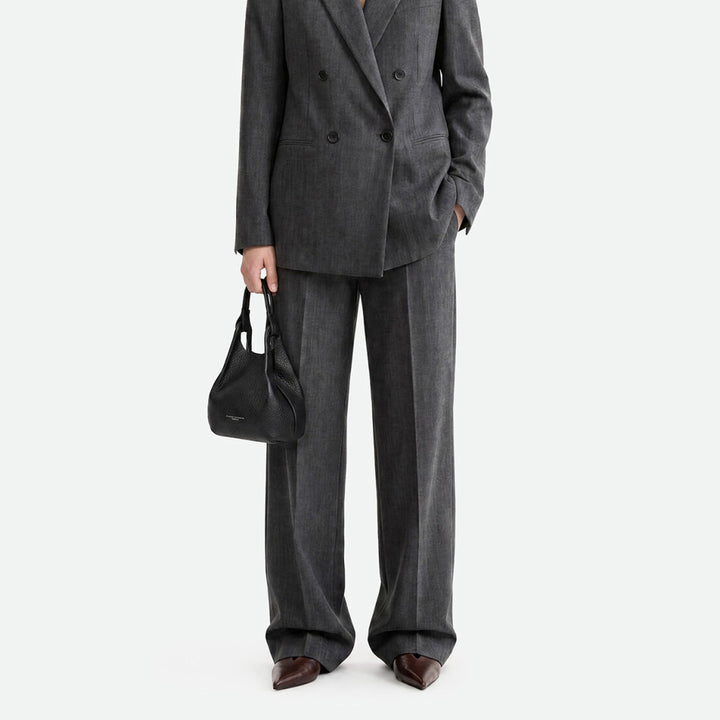 Woman in a grey suit carrying a small black leather bag at her side