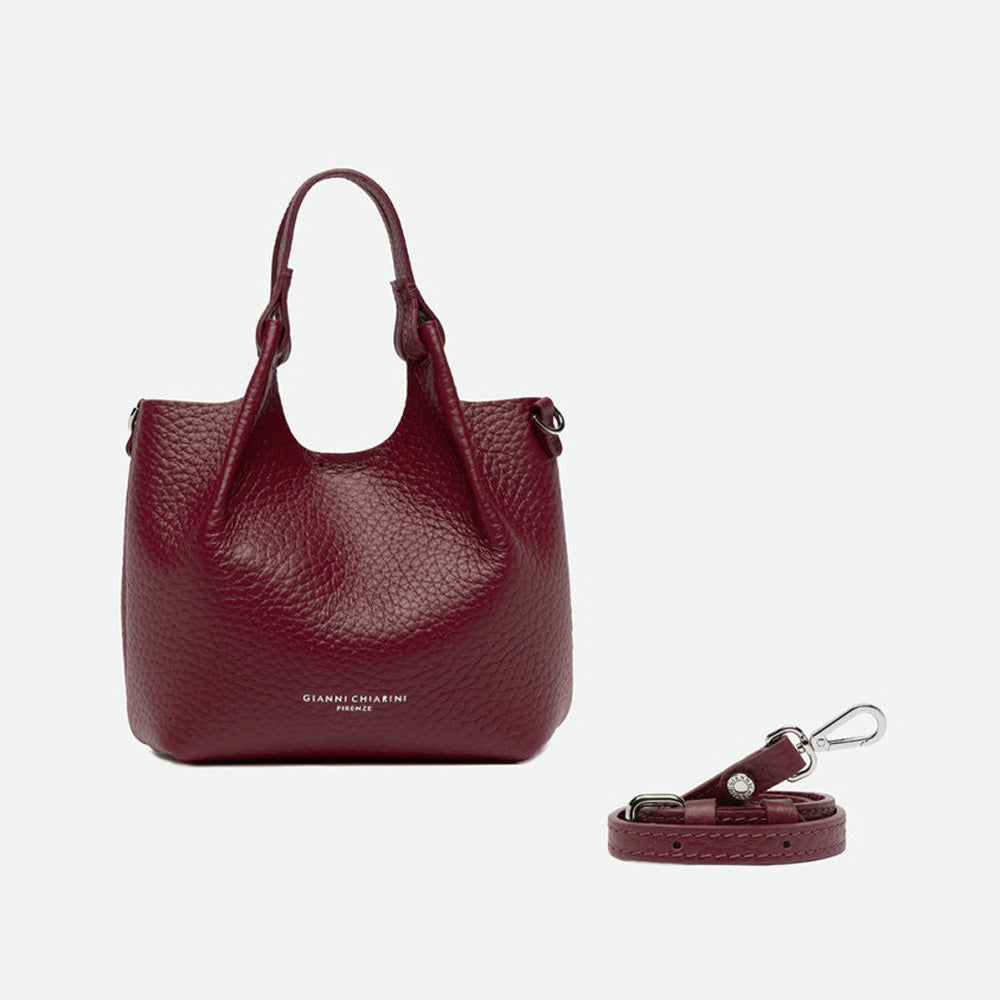 Small deep red leather tote with its sides opened out, beside a separate shoulder strap