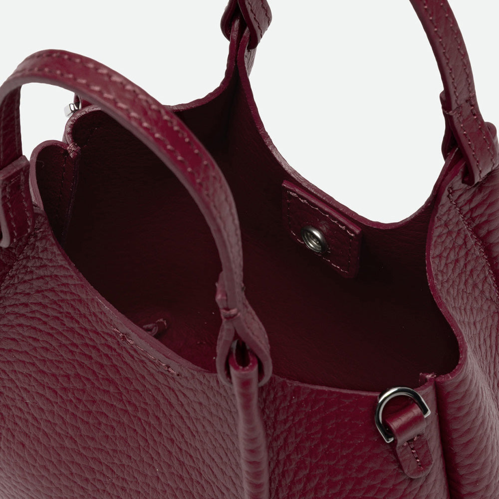 Inside a deep red leather bag showing the unlined interior and knotted handles