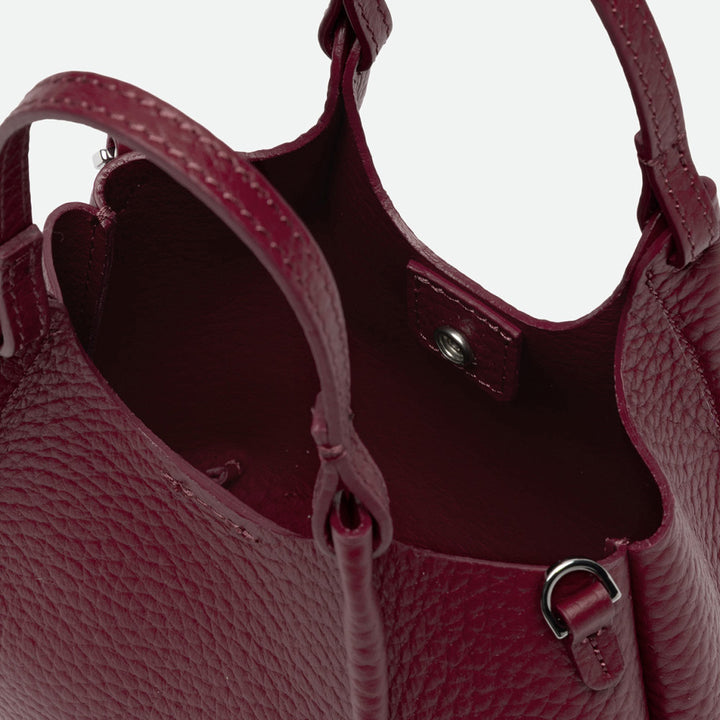 Inside a deep red leather bag showing the unlined interior and knotted handles