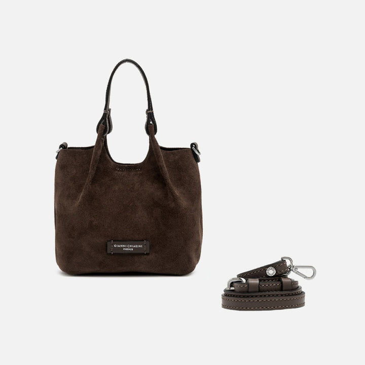 Small dark brown suede tote with its sides opened out, beside a separate shoulder strap