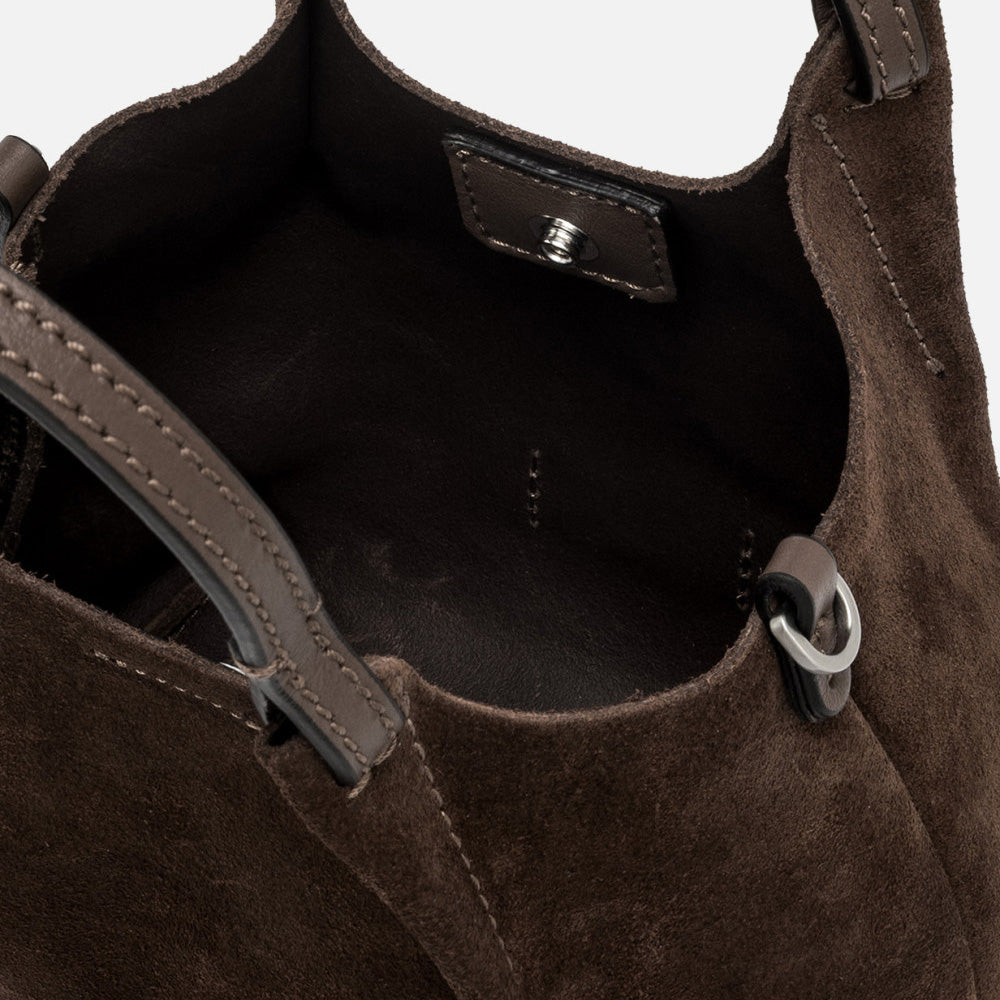 Inside a dark brown suede bag showing the interior and magnetic clasp