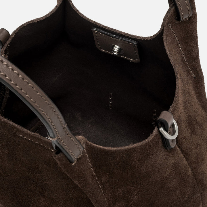 Inside a dark brown suede bag showing the interior and magnetic clasp