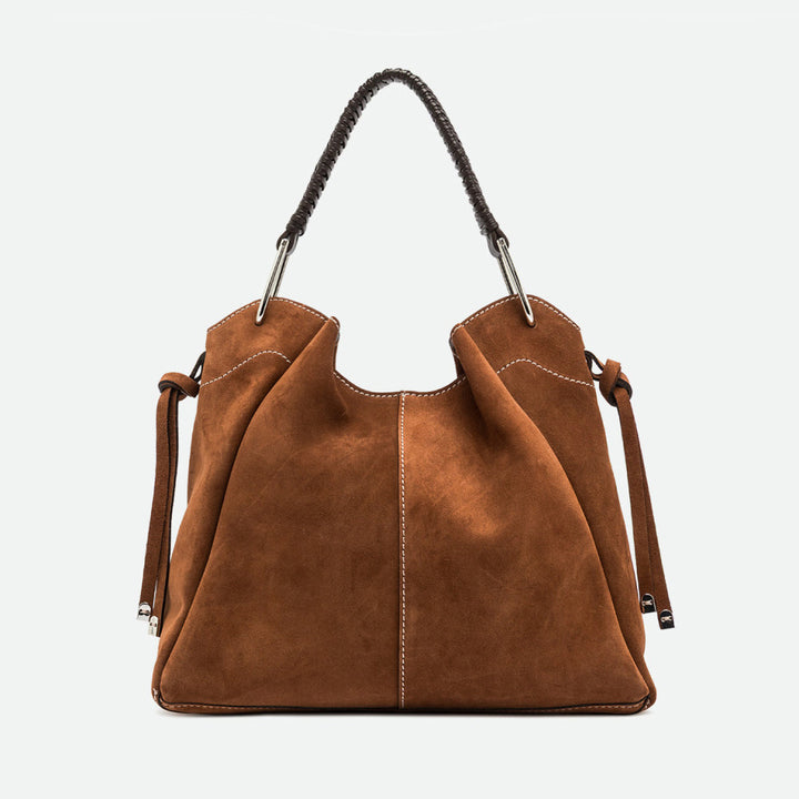 Front of a large tan suede shoulder bag with buckled side straps
