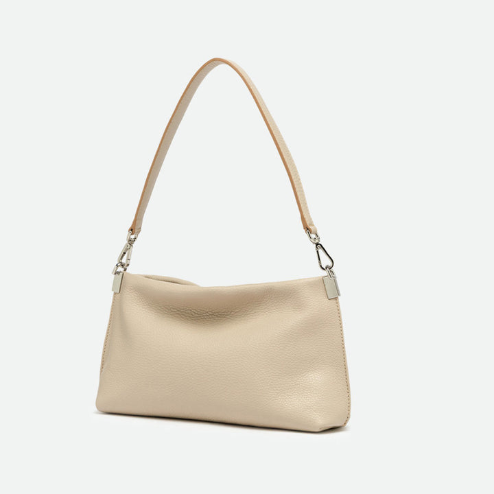 Side view of a slim cream leather shoulder bag with silver clasps