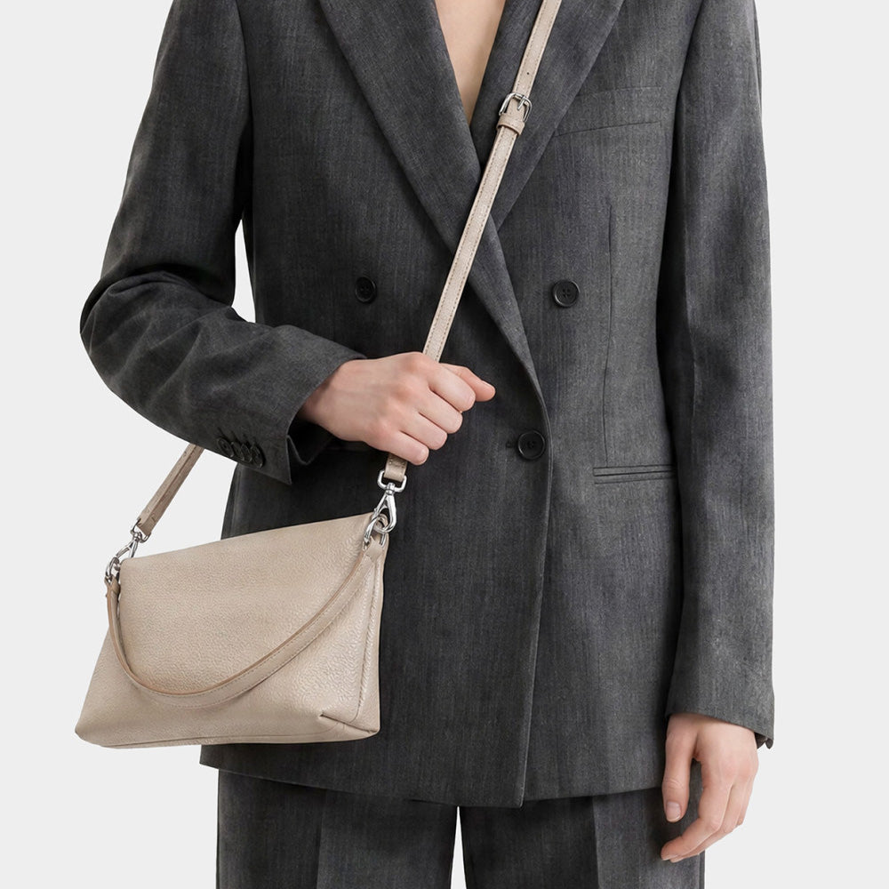 Woman in a grey blazer wearing a cream leather bag across the body