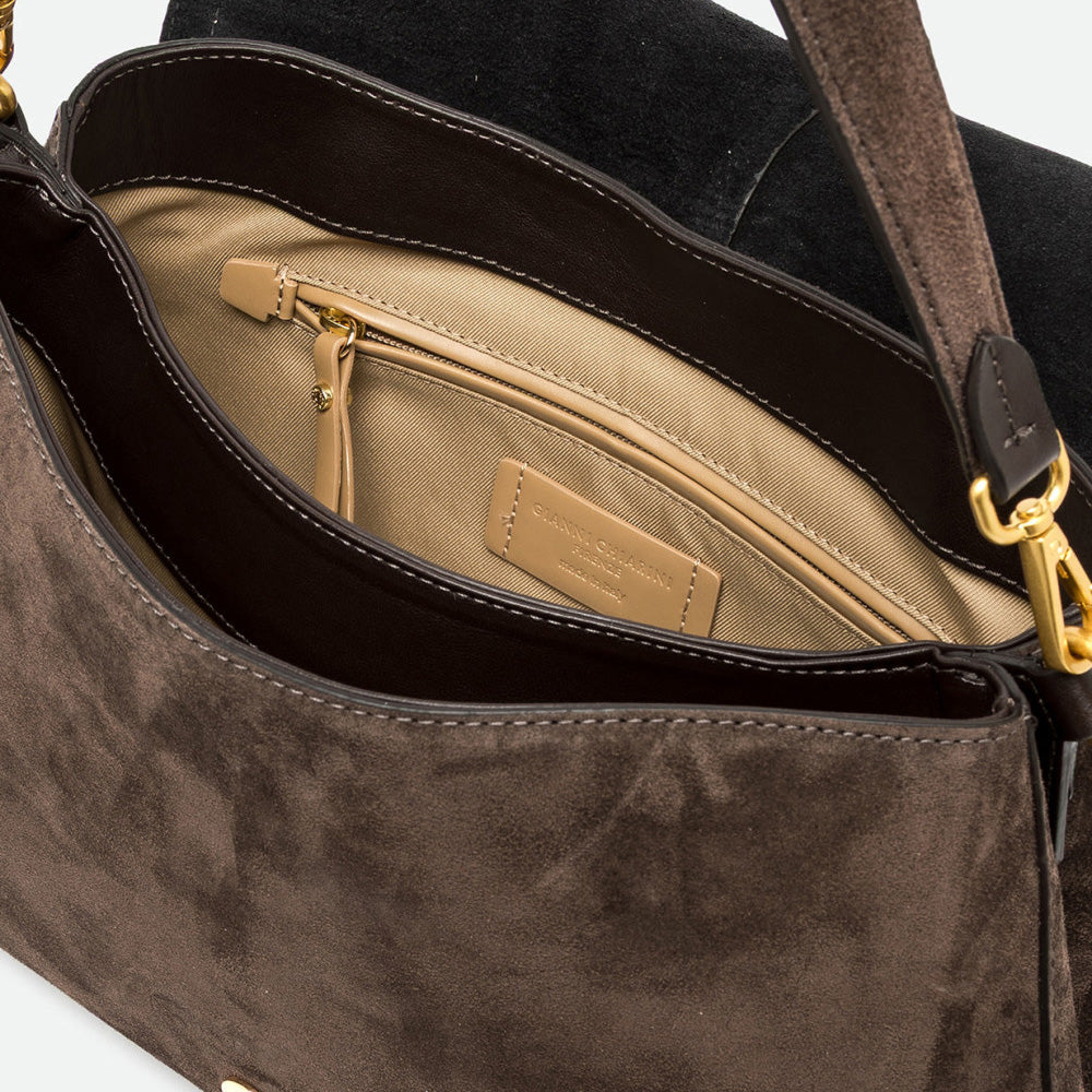 Inside a dark brown suede bag showing a beige lining and zip pocket