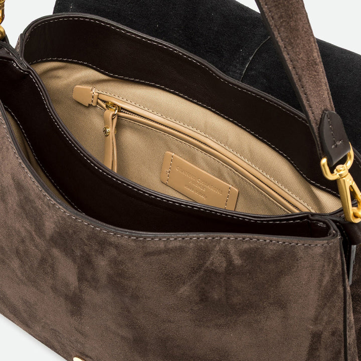 Inside a dark brown suede bag showing a beige lining and zip pocket