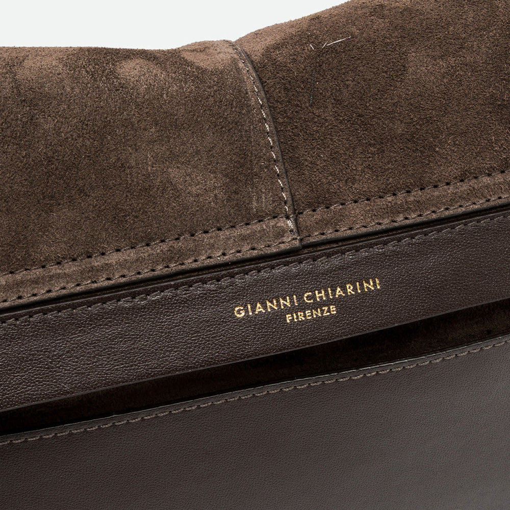 Close-up of dark brown suede with stitched edges and a gold embossed logo