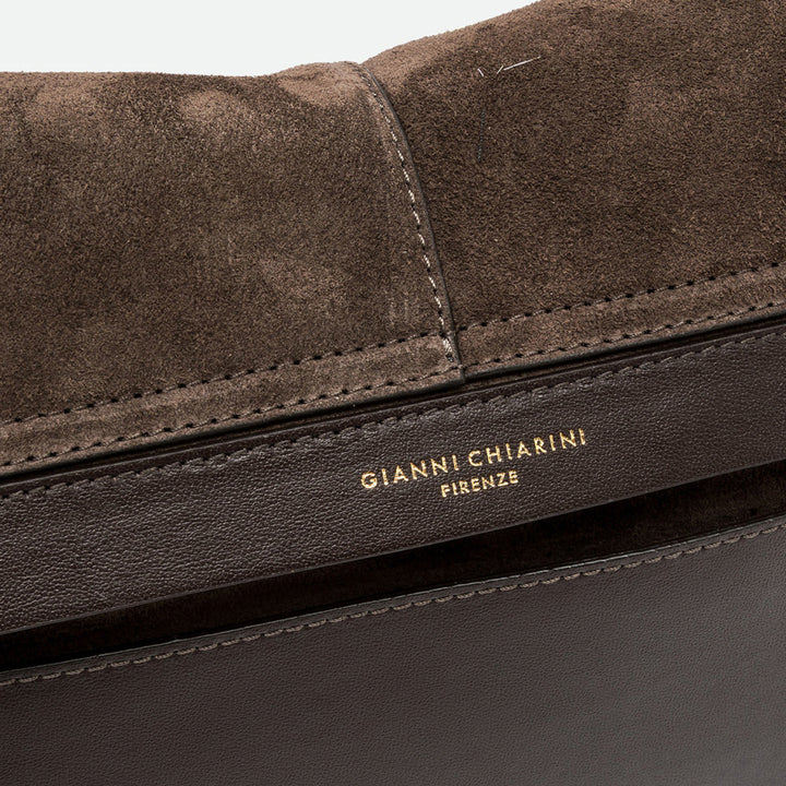 Close-up of dark brown suede with stitched edges and a gold embossed logo
