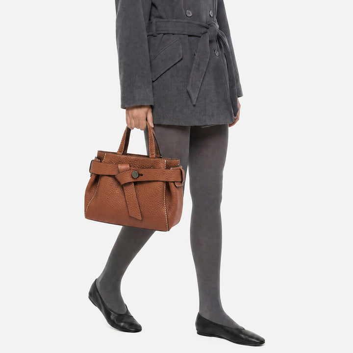 Woman in grey tights carrying a tan leather top handle bag