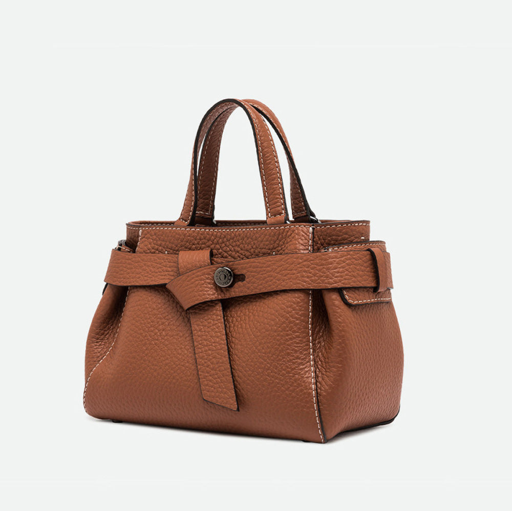 Angled view of a tan leather top handle bag with its belted front