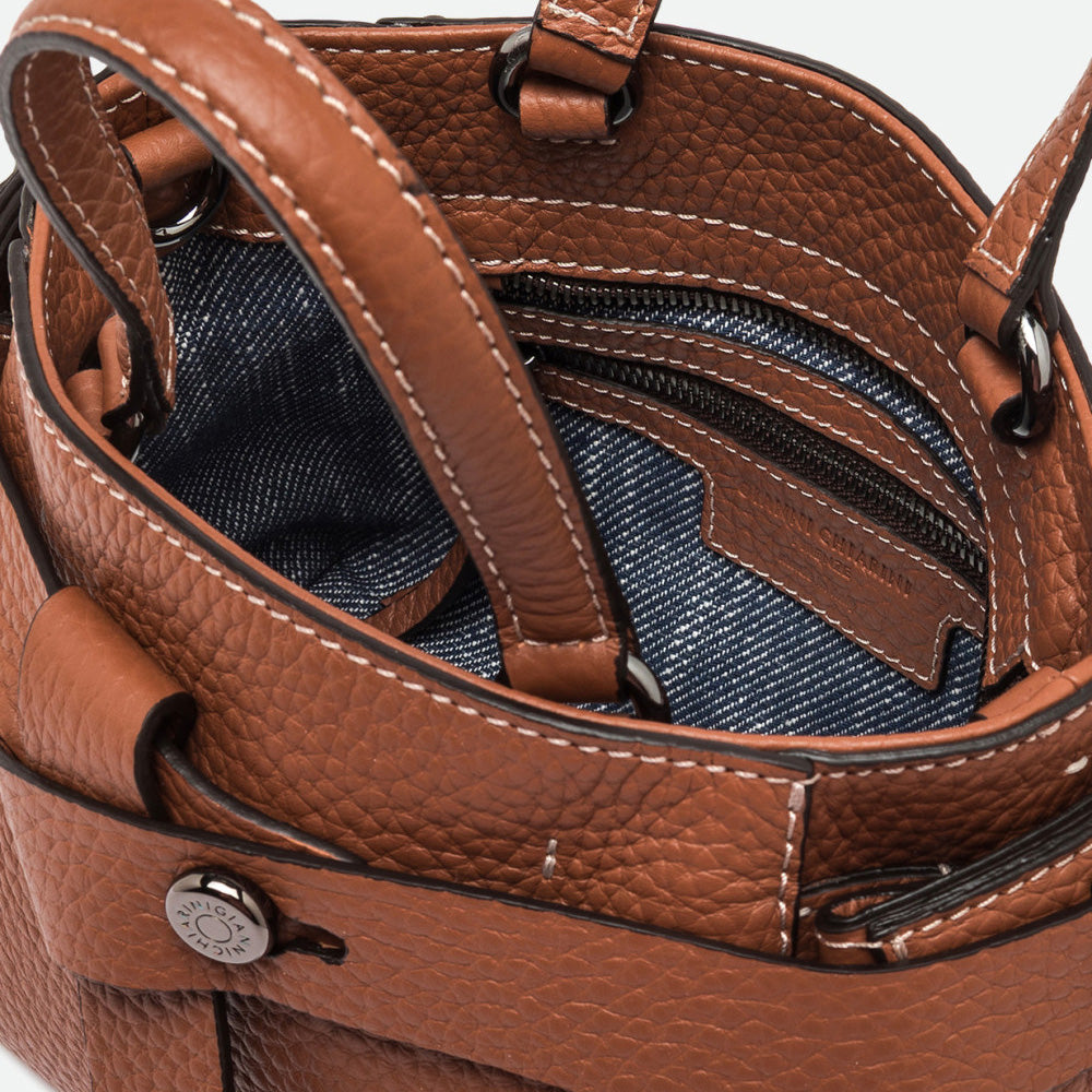 Inside a tan leather bag showing a blue denim-look lining and zip pocket