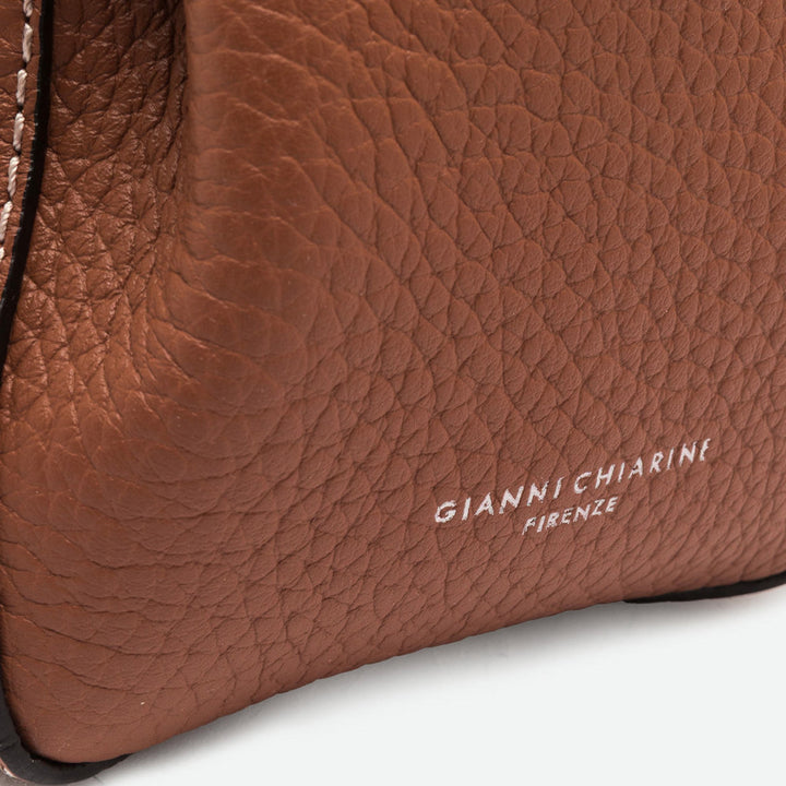 Close-up of tan pebbled leather with contrast stitching and an embossed logo