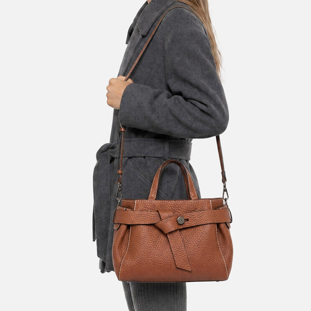 Woman in a grey coat wearing a tan leather bag across the body