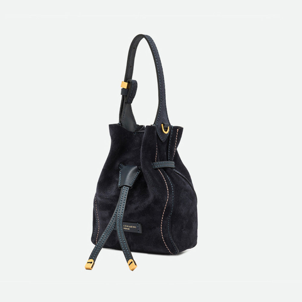 Side view of a navy suede bucket bag with gold-tipped drawstrings