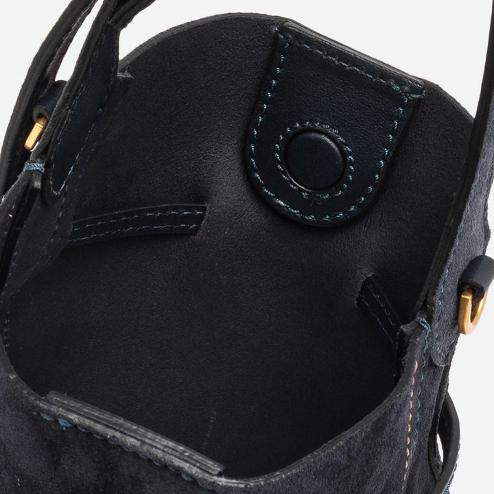 Inside a navy suede bucket bag showing the navy interior and leather tab