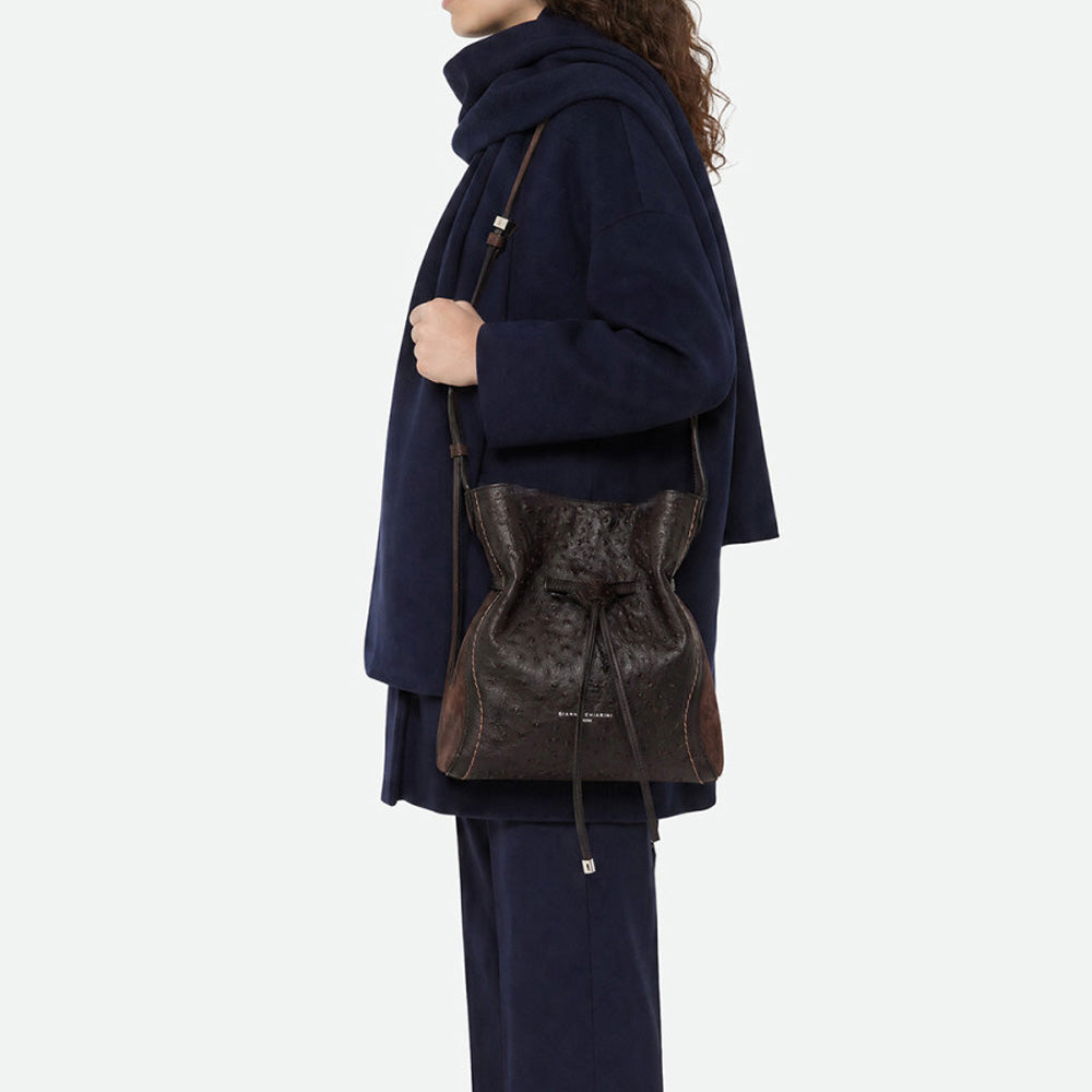 Woman in a navy jumper wearing a dark brown leather bucket bag across the body