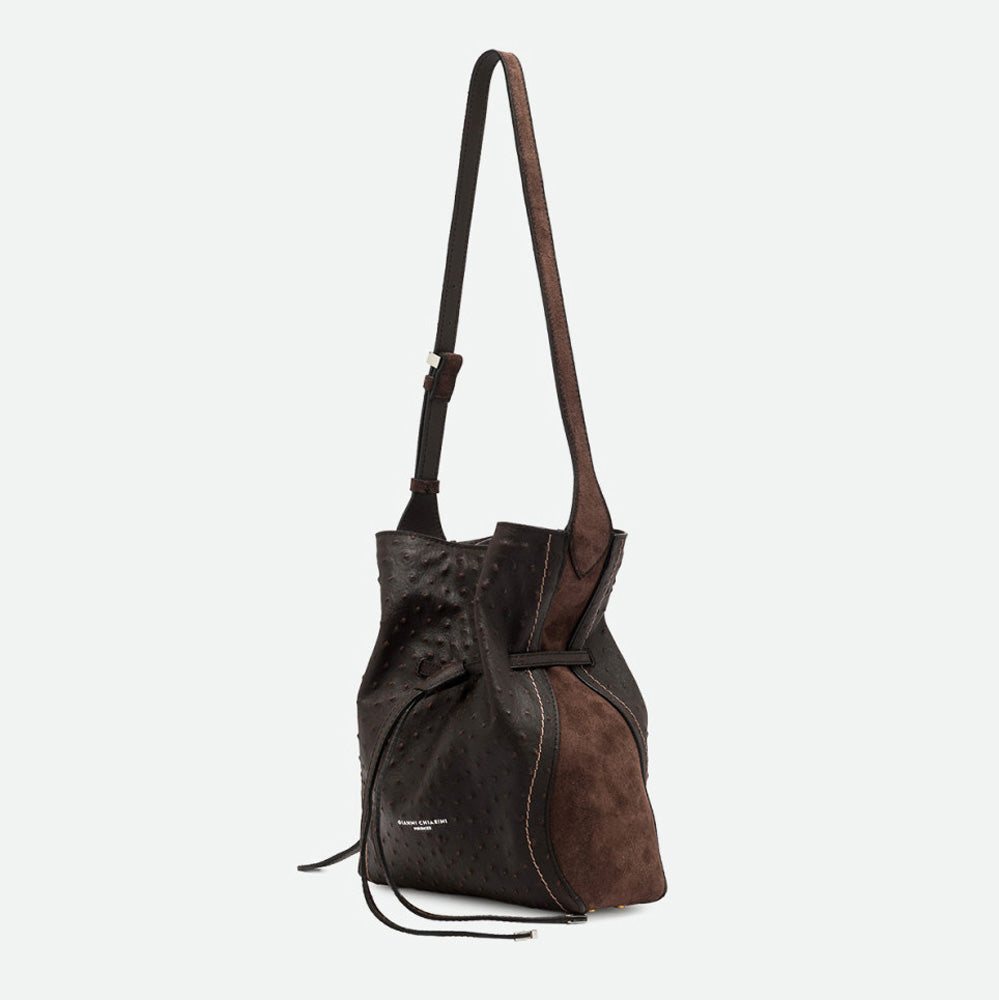 Side view of a dark brown bucket bag showing a brown suede side panel