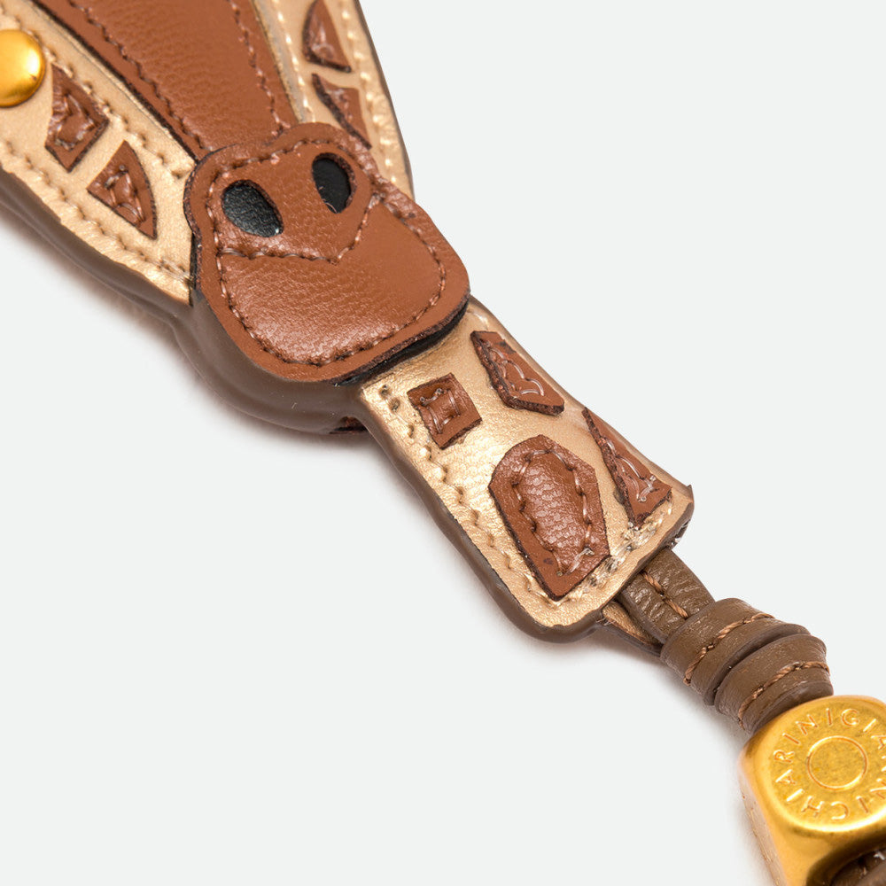 Close-up of a giraffe bag charm showing its patchwork face and gold bead