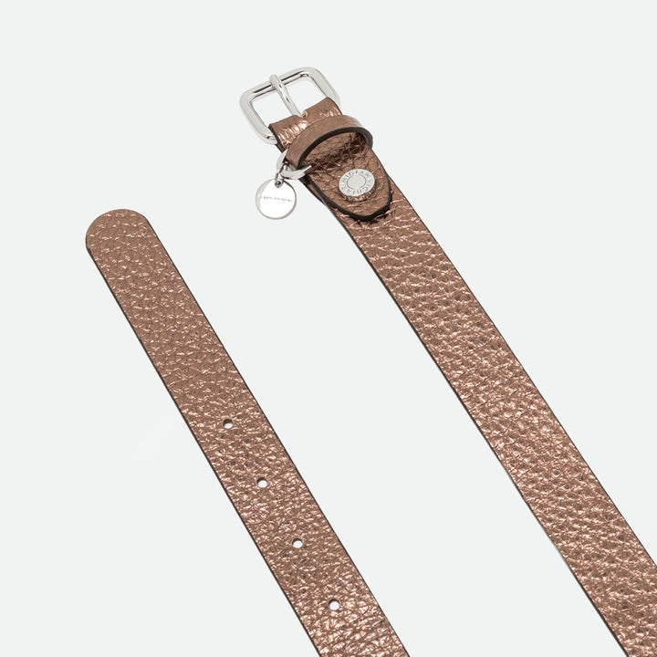 Close-up of a bronze metallic leather belt showing the silver buckle and punched holes