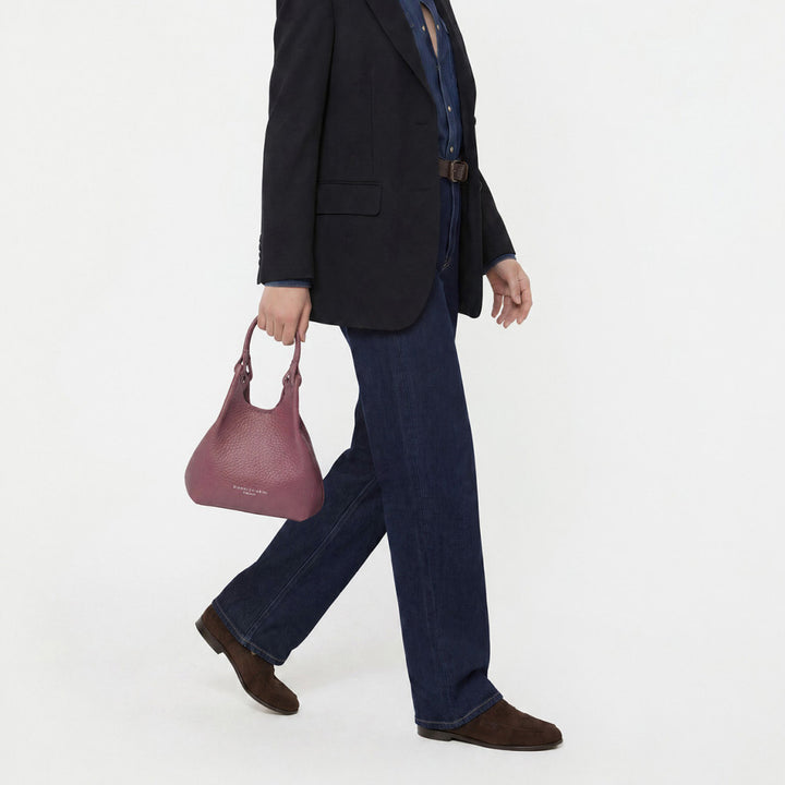 Woman in jeans and a black blazer carrying a small dusty pink bag