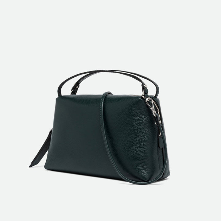Angled view of a dark green leather handbag with its crossbody strap attached