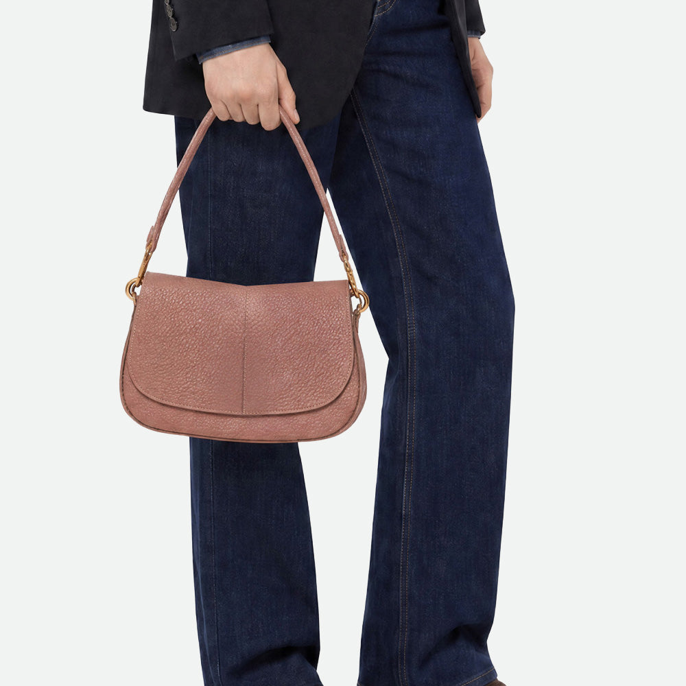 Woman in jeans carrying a dusty pink leather shoulder bag by its strap