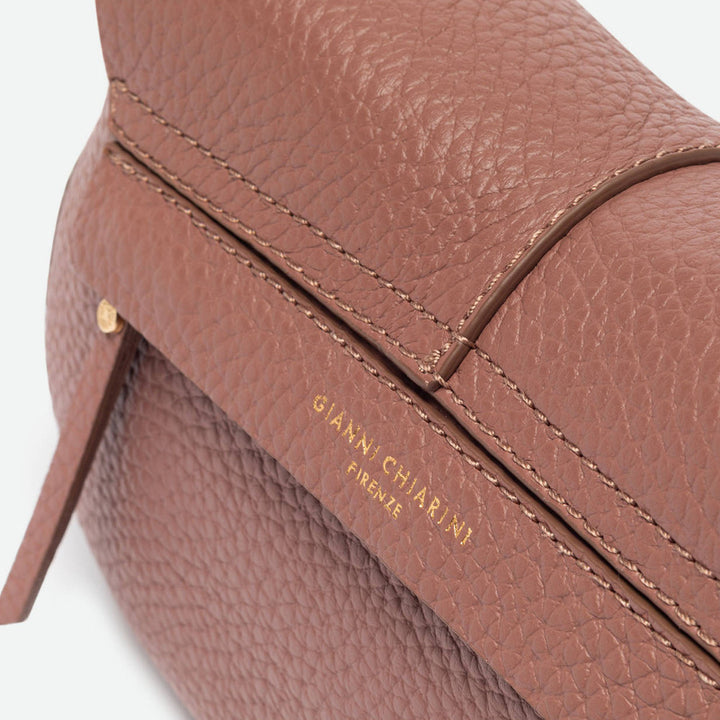 Close-up of dusty pink pebbled leather with contrast stitching and a gold logo