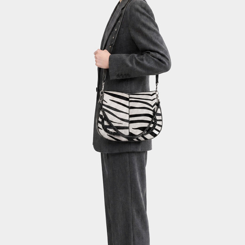 Woman in a grey suit wearing a zebra print bag on her shoulder