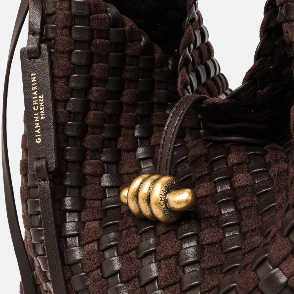 Close-up of a sculpted gold knot clasp on dark brown woven leather