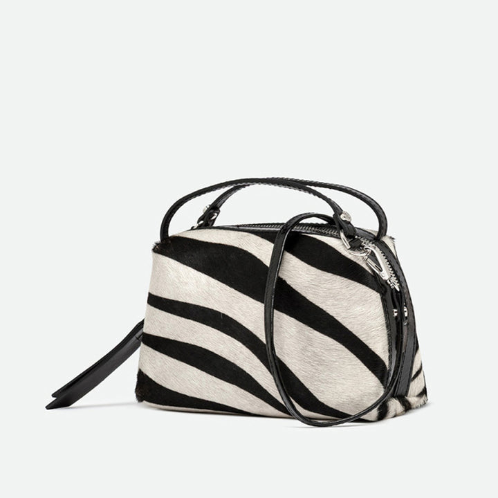 Angled view of a zebra print handbag with its crossbody strap attached
