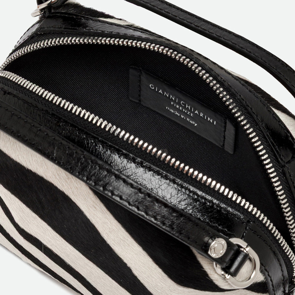 Inside a zebra print handbag showing a black lining and silver zip
